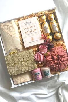 the contents of a gift box are laid out on a white sheet with pink and gold accessories