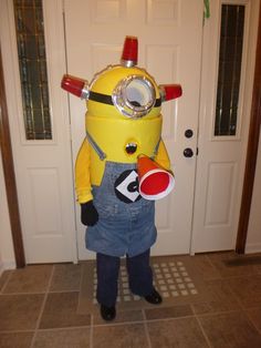 a little boy dressed up as a minion in front of a door wearing an apron and hat