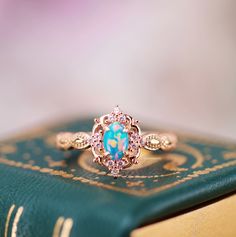 The Vintage Blue Fire Opal Engagement Ring is a breathtaking homage to timeless romance and natural beauty, meticulously crafted to evoke the enchantment of a bygone era. Inspired by the splendor of nature, this exquisite ring is a testament to love's enduring power and the magic it ignites. ►At its center rests a magnificent blue fire opal, radiating with an otherworldly iridescence that evokes the tranquil depths of the ocean and the boundless expanse of the sky. Set within a sumptuous 14K rose gold vermeil band, the opal exudes an ethereal allure, captivating the beholder with its mesmerizing play of colors. ►Drawing inspiration from the wonders of the natural world, the ring's design is adorned with delicate details reminiscent of blooming flowers and winding vines. Each intricately cr Heirloom Rose Gold Opal Ring Gift, Oval 14k Rose Gold Wedding Jewelry, 14k Rose Gold Halo Design Jewelry Gift, Rose Gold Opal Ring With Halo Setting, Rose Gold Opal Promise Ring, Heirloom Style Rose Gold Opal Ring For Anniversary, Blue 14k Gold Opal Wedding Ring, Rose Gold Opal Promise Ring With Prong Setting, Rose Gold Opal Ring With Accent Stones For Wedding