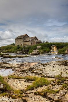 an old house sitting on top of a hill next to a river