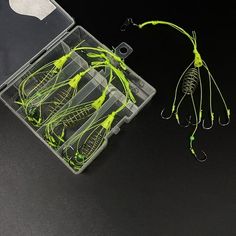 some green and yellow fishing lures in a plastic box on a black surface with an apple logo