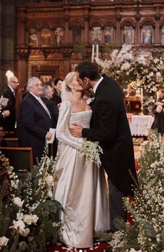 a bride and groom kiss in front of the alter at their wedding ceremony, surrounded by guests