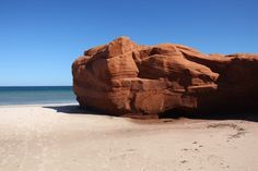 a large rock sitting on top of a sandy beach