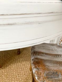 a white surfboard sitting on top of a wooden table next to a bench and rug