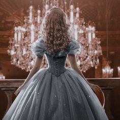 a woman in a ball gown looking at a chandelier