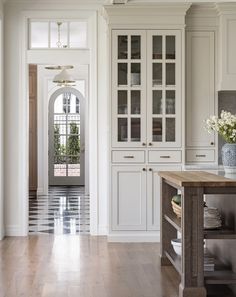 a large kitchen with white cabinets and wood flooring on the side walk leading to an entry way