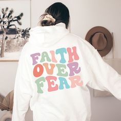 "Faith Over Fear Hoodie Christian Hoodie Preppy Christian Sweatshirt Trendy Clothes Oversized Aesthetic Words on Back Cute Bible Verse Shirt ~ PRODUCT DETAILS ~ ❤ If a size or color is not showing available, please message me. Stock can change daily and I may be able to order it for you. ❤ Gildan Brand ❤ Front Pocket design is 4\"x4\" ❤ 50% Cotton, 50% Polyester ❤ DTG (Direct to Garment) Printing. The Ink is printed directly into the fabric. There is no Vinyl used. ~ SIZING ~ ❤ Unisex Sizing ❤ P White Hoodie With Letter Print For Loungewear, Oversized White Hoodie With Slogan, Euphoria Hoodie, Hoodies Men Style Fashion, Cute Bible Verses, Front Pocket Design, Oversized Aesthetic, Preppy Sweatshirts, Cute Bibles