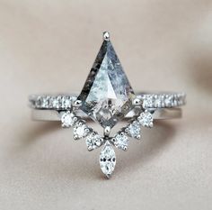 an engagement ring with a pear shaped diamond surrounded by smaller pear shaped diamonds on top