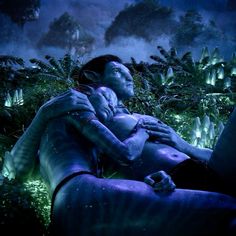 a man and woman are laying in the grass with glowing lights around them, as if they were hugging or kissing