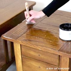 a person using a brush to paint a wooden table