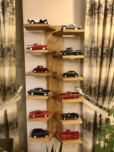 a wooden shelf filled with toy cars on top of it's sides next to a potted plant