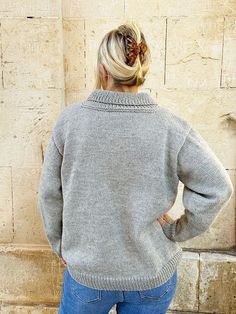 a woman standing in front of a stone wall with her back turned to the camera