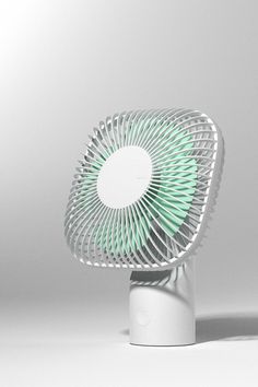 a white and green fan sitting on top of a table next to a gray wall