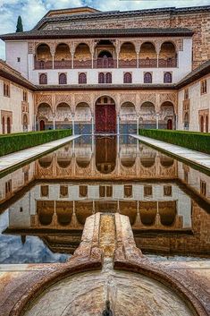 the reflection of an old building in a water fountain with its reflection on the ground