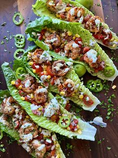 lettuce wraps filled with shrimp, tomatoes and corn on a wooden cutting board