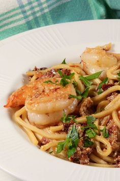 a white plate topped with pasta and shrimp