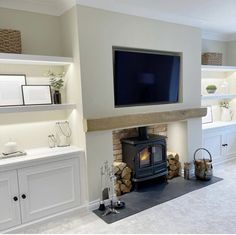 a television mounted on the wall above a fire place in a room with white cabinets