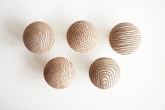 four wooden bowls are arranged on a white surface, each with different patterns and sizes