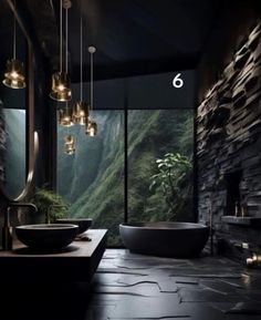 a bathroom with stone walls and flooring, lights hanging from the ceiling over the bathtub