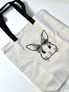 a tote bag with a drawing of a rabbit on it's side and black handles