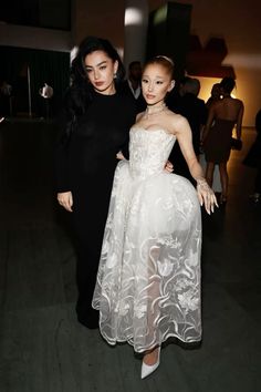 two women standing next to each other in formal wear and one is wearing a white dress