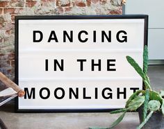 there is a sign that says dancing in the moonlight next to a cactus and knife