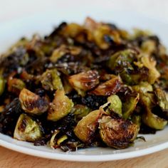 a white plate topped with brussel sprouts on top of a wooden table