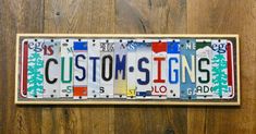 a license plate with the word custom - signs on it is mounted on a wooden wall