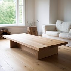 a wooden table sitting in front of a window next to a white couch on top of a hard wood floor