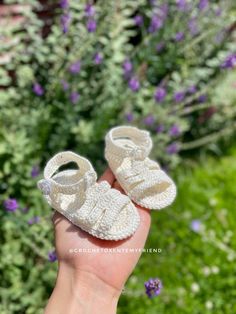 someone is holding their baby shoes in front of some flowers