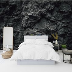 a bedroom with black rock wallpaper and white bedding