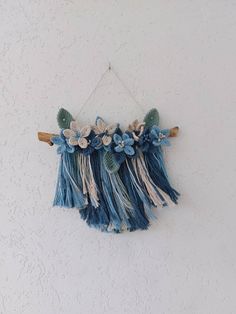 a piece of art hanging on the wall with blue and white feathers attached to it