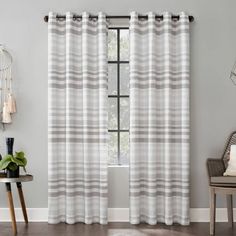 a white and gray striped curtain hanging on a wall next to a chair with a potted plant