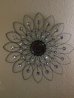 a metal wall decoration with glass beads on the center and leaves in the middle, hanging from a ceiling