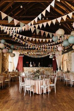 a room filled with tables and chairs covered in paper garlands hanging from the ceiling