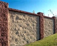 a brick wall with grass growing on the side and blue sky in the back ground