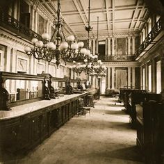 an old black and white photo of a long room with chandeliers hanging from the ceiling