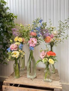 four glass vases with different flowers in them