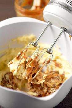 a mixer mixing food in a white bowl