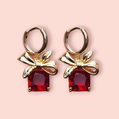 Elevate your jewelry collection with these stunning Gold Hoop Earrings featuring a beautiful red gemstone and an elegant bow accent. Perfect for any special occasion or as a thoughtful gift, these earrings are designed to captivate and add a touch of sophistication to your style. Details: Material: High-quality copper, plated with 14K real gold for a luxurious and lasting finish. Gemstone: Vibrant red cubic zirconia that adds a pop of color and elegance. Design: Features a chic bow accent that c Red Gemstones, Bow Design, Copper Plated, Jewelry Earrings Hoops, Perfect Gift For Her, Gold Hoop, Elegant Jewelry, Gold Hoop Earrings, Vibrant Red