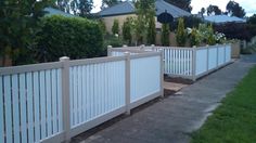 a white picket fence next to a sidewalk