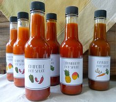 six bottles of hot sauce sitting next to each other on a table with napkins