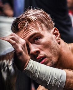 a man with bandages on his arm leaning against a wall