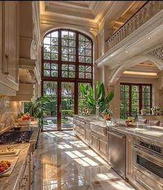 a large kitchen with marble counter tops and stainless steel appliances in front of an arched window