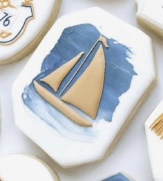 decorated cookies with blue and white icing on top of each other, including a sailboat