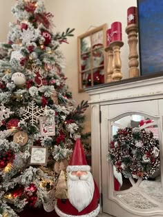 a decorated christmas tree next to a fireplace with a santa clause decoration on the mantle