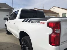 a white truck parked in front of a house with a black stripe on the tailgate