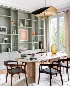 the dining room table is surrounded by chairs and bookshelves with open shelving behind it