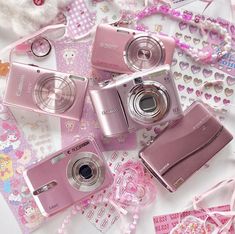 there are many different pink cameras on the table with hearts and other things around them