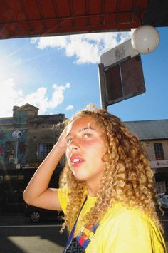 a woman with curly hair is standing under a street light and looking up at the sky